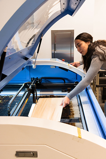 Emely Villa using a laser cutter in the SEC Engineering stockroom