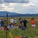 students and instructor in a field with instruments