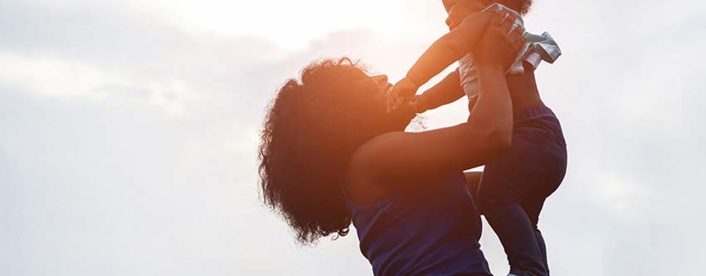 smiling mother holding up young child