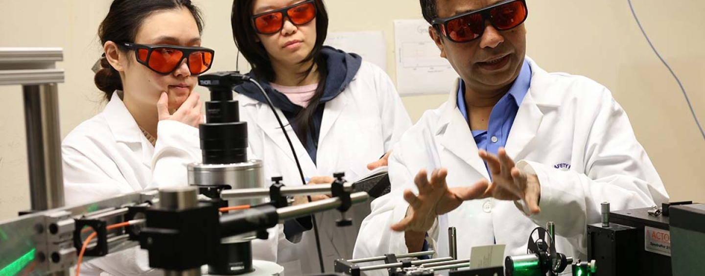 Professor Newaz and two students look at lab equipment