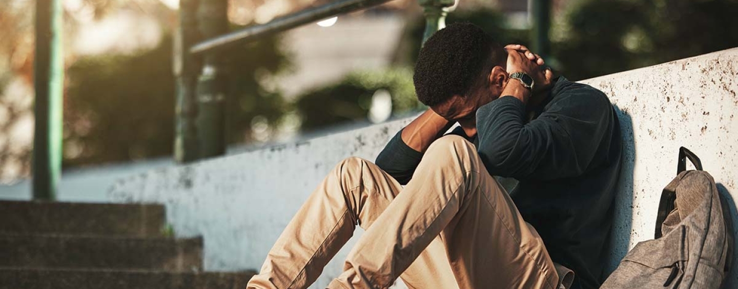 Man of color sitting against low wall