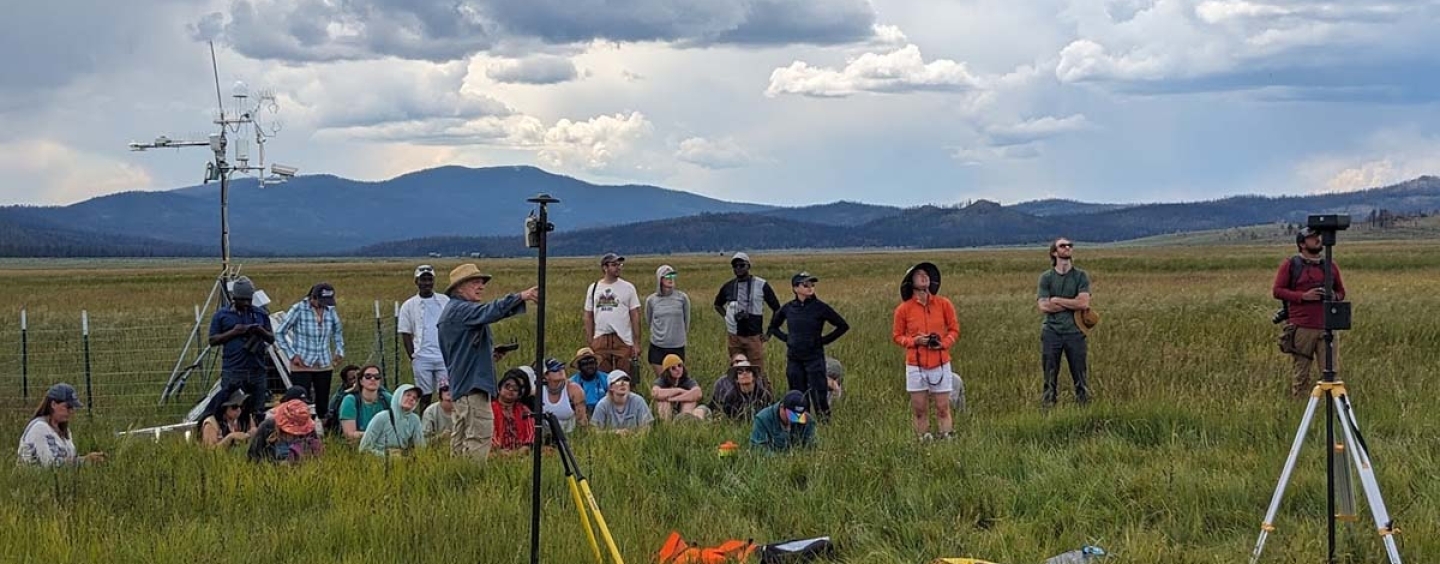 students and instructor in a field with instruments