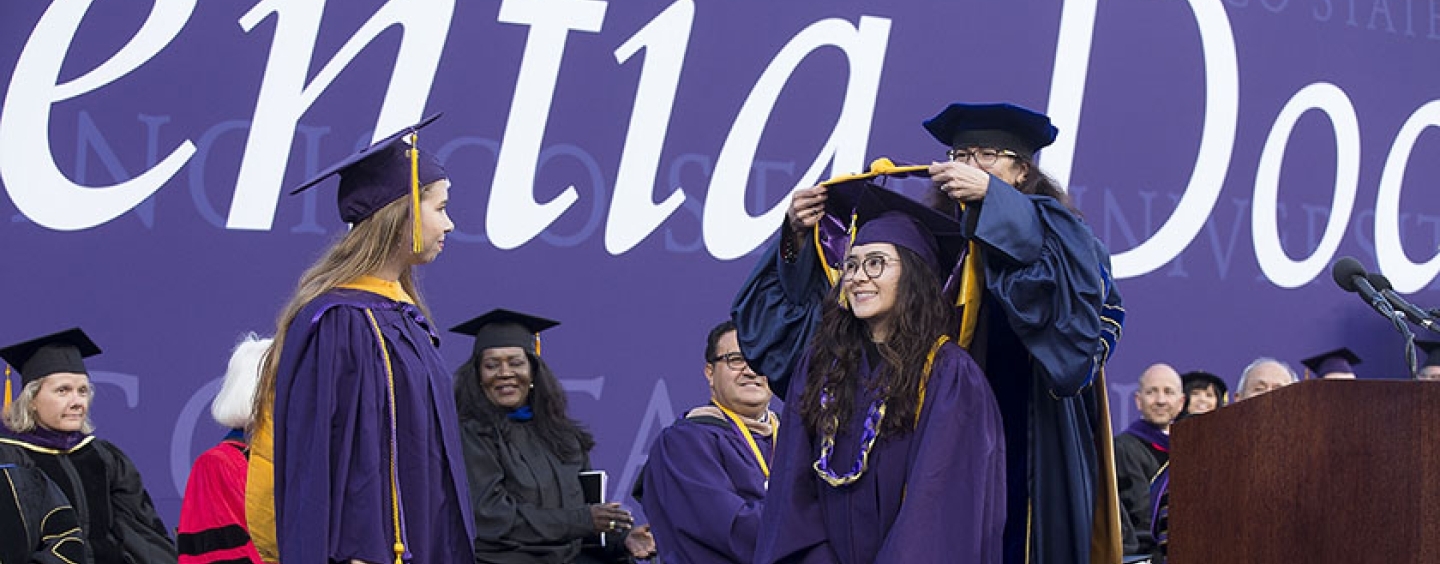 students receive their hoods at graduation ceremony